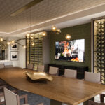 Elegant dining room with a long wooden table, modern lighting, and a wall of wine bottles. A screen displays a person cooking.
