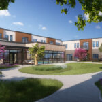 Modern two-story building surrounds a lush courtyard with vibrant trees and flowers, under clear blue skies. Pathway and benches add tranquility.